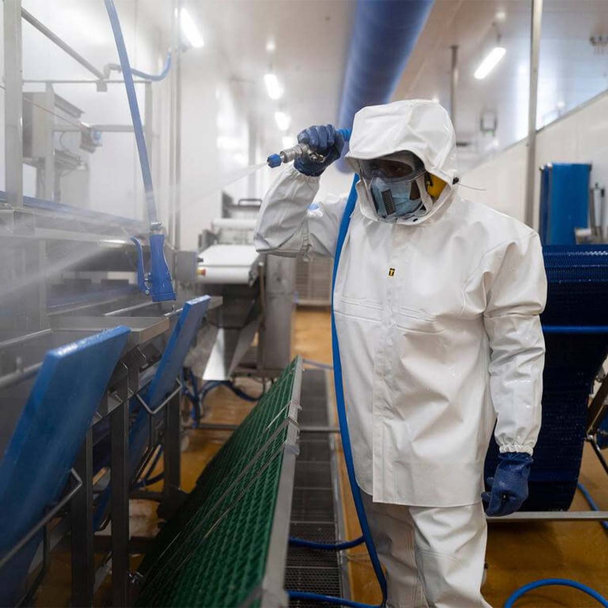 Person wearing Guy Cotten Heracles chemical resistant jacket and bib & braces while cleaning food processing facility