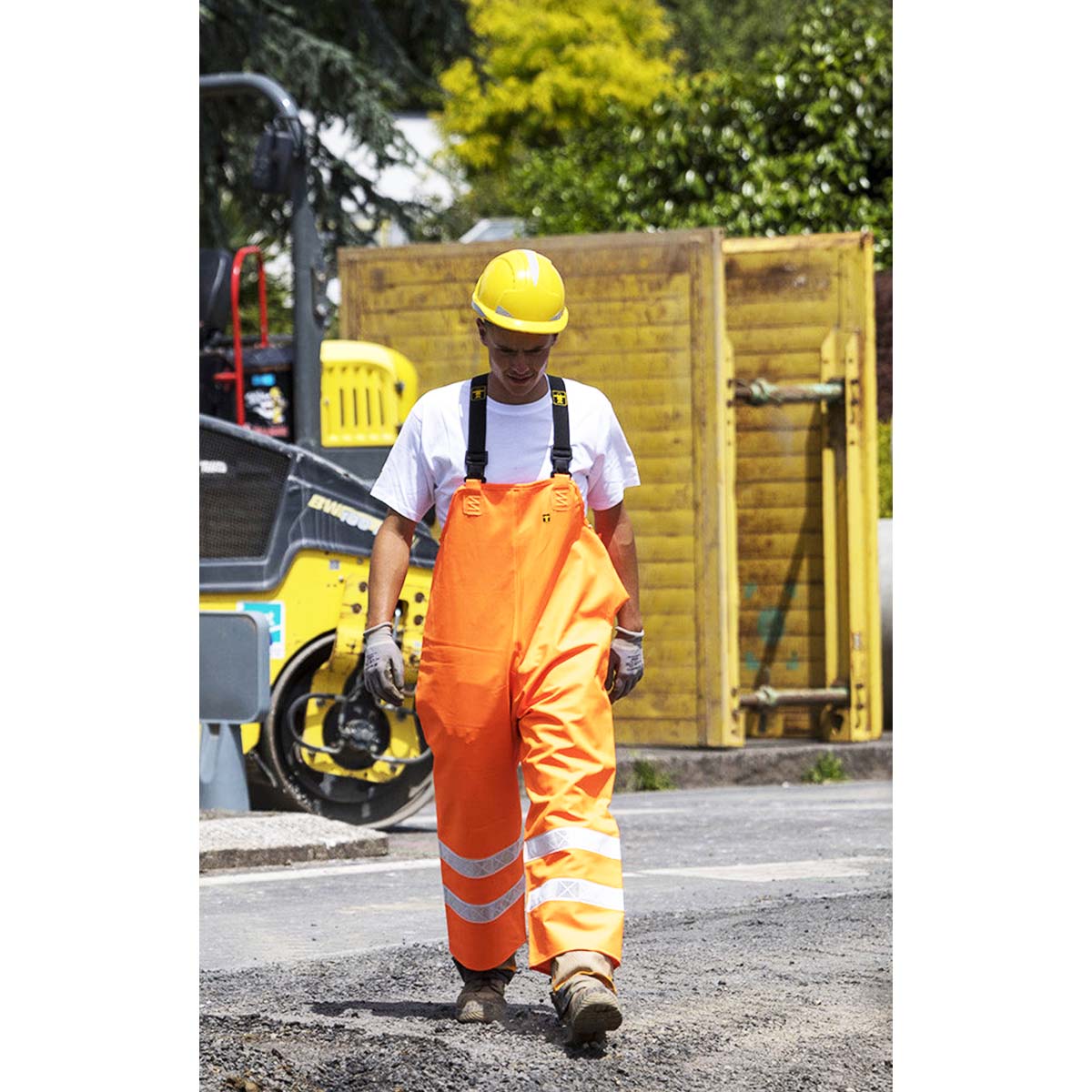 Worker in Guy Cotten high vis Hitflash waterproof orange overalls and yellow hard hat on a construction site