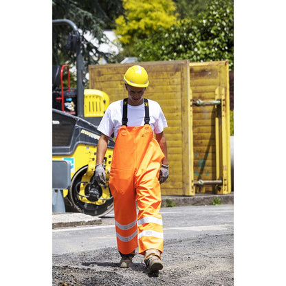 Worker in Guy Cotten high vis Hitflash waterproof orange overalls and yellow hard hat on a construction site